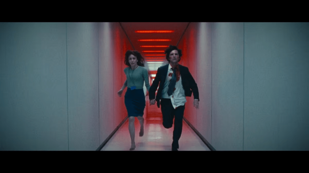 Helly and a bloody, disheveled Mark S. run through the hall at Lumon while red lights flare behind them